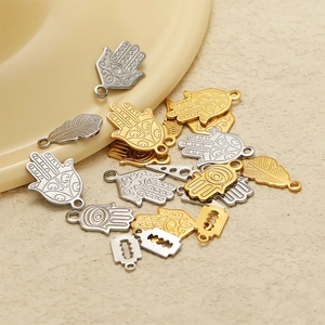 Detailed shot of gold and silver Hamsa Hand, feather, and razor blade charms for DIY jewelry