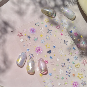 Detail of colorful star and heart embossed nail art stickers on pearlescent false nails