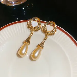 Vintage heart and long waterdrop pearl earrings with gold hollow design on porcelain