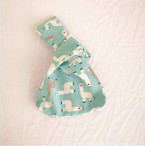 Detail of mint green linen wrist bag with cute alpaca pattern on white background