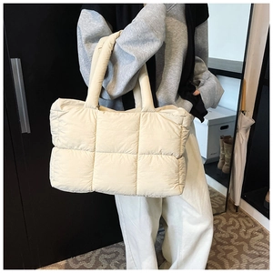 Detail of a large cream quilted puffer tote bag with thick padded shoulder handles