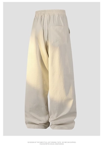 Detailed view of elastic drawstring waist and heavy texture on cream wide-leg trousers