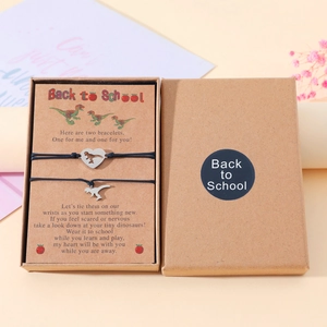 Detailed view of two dinosaur heart charms on black ropes in a Back to School gift box