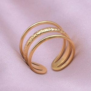 Detail of a three-layered gold ring featuring a hammered texture and open adjustable band