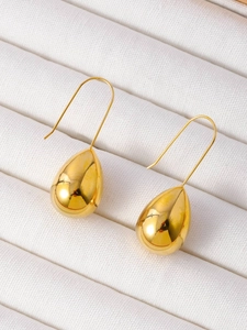 Detailed view of polished gold teardrop earrings placed on a white velvet jewelry box