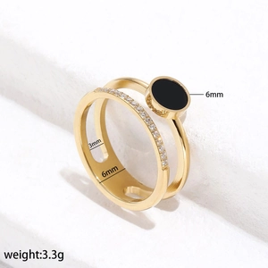 Detailed view of dual-band gold ring with black disc and sparkling zircon accents
