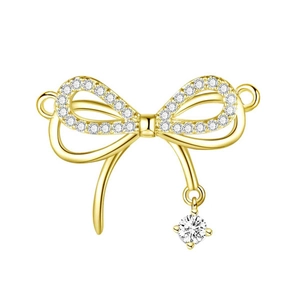 Detailed view of a gold bow-knot pendant with sparkling zircons on a white background