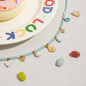 Flat lay of beaded necklace with light blue crystal beads and gold heart star pendants
