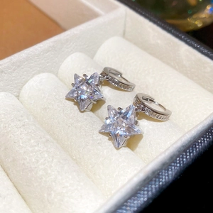 Detailed macro view of silver star earrings with zircon inlay in a white jewelry box