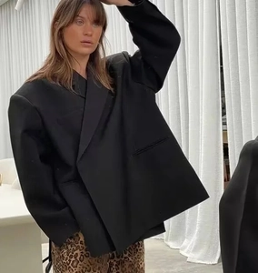 Détail d'un blazer noir surdimensionné avec col à revers et fermeture boutonnée latérale