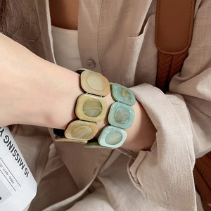 Detail of square resin beaded stretch bracelets in amber and light green on a model wrist