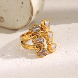 Close-up of gold 18K plated double layer ring with drop-shaped zircon on stone texture