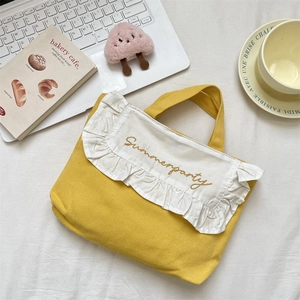 Close-up of a yellow canvas lunch bag with ruffle edges and Summerparty embroidery