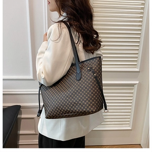 Detail of deep brown tote bag with geometric dot pattern worn over a white suit