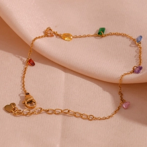 Detail of 18K gold-plated chain with colorful zircon gems on soft pink fabric