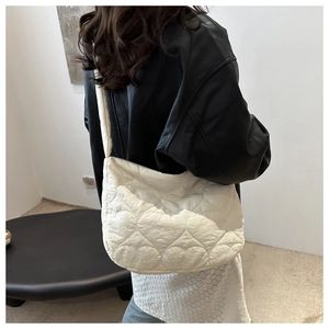 Detail showing white heart-quilted puffer tote bag worn over a black leather jacket