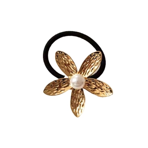 Golden starfish metal hair tie with textured petals and pearl center on black elastic