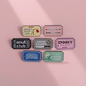 Flat lay of colorful enamel pins with book genres like Romance and True Crime themes