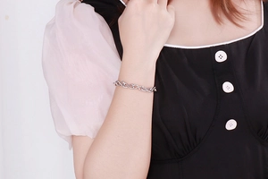 Polished stainless steel infinity symbol bracelet on a woman's wrist with a white background