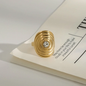 Detail of a gold stainless steel ring with concentric circles and a crystal on a book