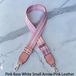Adjustable woven bag strap in pink with white arrow patterns and gold metal hardware
