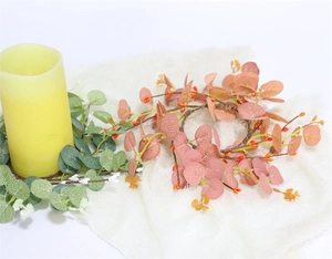 Detail view of eucalyptus wreath with pink leaves and berries around a candle