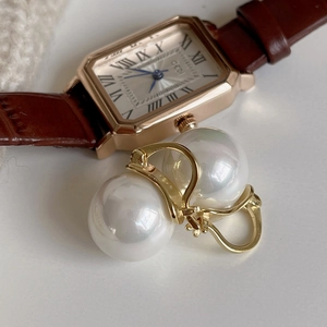 Elegant set with large pearl stud earrings and a vintage gold watch with brown strap