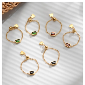 Detail of adjustable gold chain rings with rectangle green and red zircon gemstones