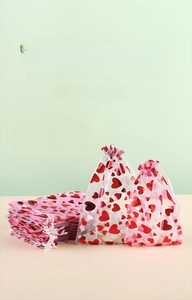 Detail of drawstring organza gift bags with gold heart patterns for weddings and parties