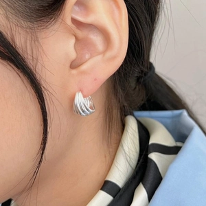 Macro view of minimalist layered silver hoops worn on the ear showing polished texture