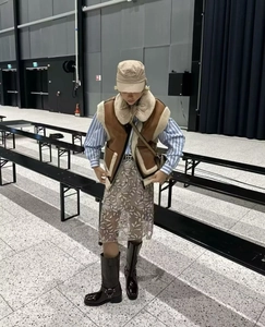 Gilet en daim marron avec bordure en peau lainée sur une chemise à rayures bleues et jupe