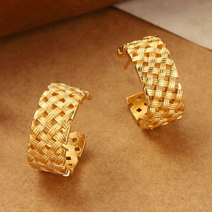 Macro shot of gold woven texture earrings with elegant C-shape design and polished finish