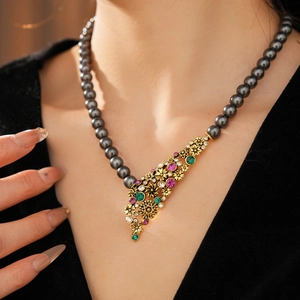 Gros plan sur un collier vintage avec perles gris foncé et pendentif fleur en cristal