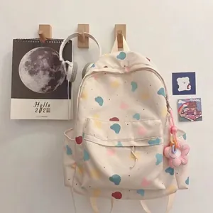 Cute cream-colored backpack with colorful heart patterns and floral charms for students
