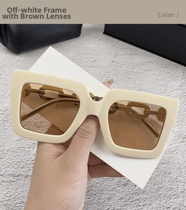 Detalle de gafas de sol crema con lentes marrones y cadena dorada en las varillas