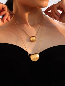 Close-up of a double-layered 18k gold-plated necklace with organic bean pendants