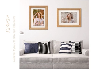 Close-up of minimalist wood photo frames on a wall above a modern sofa setup