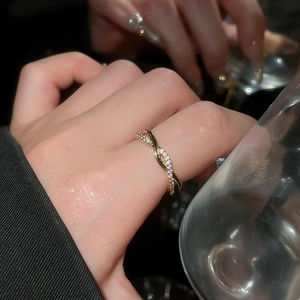 Detail of infinity crossover ring with paved zircons and gold plating on female hand
