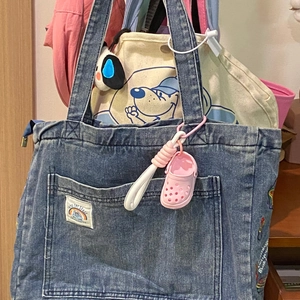 Mini pink clog shoe keychain charm attached to a denim tote bag with a white rope strap