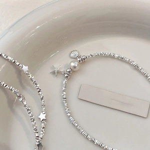 Starfish and shell pearl charm bracelet in silver stone style on a ceramic plate