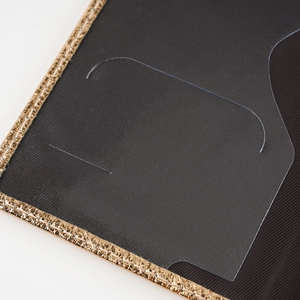 Detail of passport holder showing black twill fabric and premium gold metal trim edge