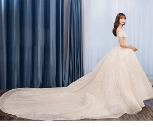Detail of champagne gold wedding dress with off-the-shoulder design and sequin train