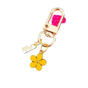 Golden keychain with yellow flower, pink heart pendant and handmade tag on white background