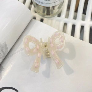 Pince à cheveux nœud blanc crème avec bordure en fil rose sur fond blanc minimaliste