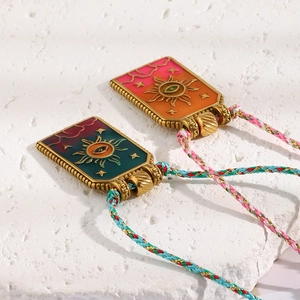 Detail of 18K gold tarot sun pendants with enamel finish on colorful braided cord