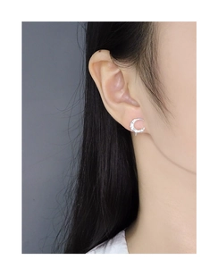 Detailed close-up of a crescent moon silver earring with pavé zircon stones on ear