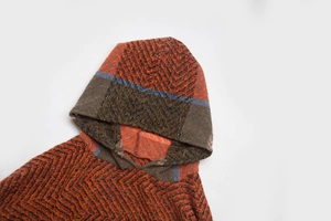 Detailed herringbone knit texture and hood construction of this orange hooded poncho cape