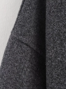 Macro shot of dark charcoal grey wool coat showing high-quality tweed fabric texture