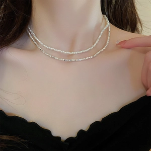 Close-up of a double-layered necklace with white pearls and irregular silver beads on a model