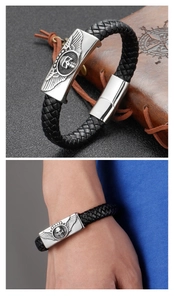 Dettaglio del bracciale in pelle nera intrecciata con ciondoli a ala e teschio d'argento